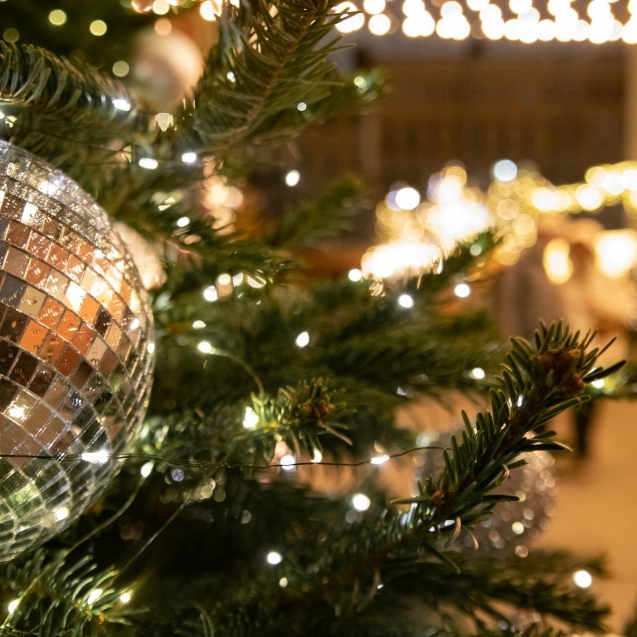 Een mooie kunstkerstboom in een zakelijke ruimte met kerstballen en verlichting.