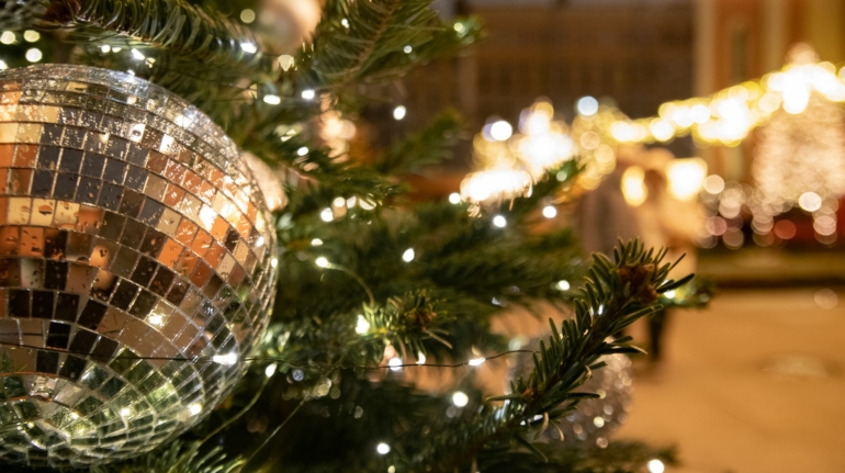 Een mooie kunstkerstboom in een zakelijke ruimte met kerstballen en verlichting.